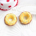 Macro view of chocolate donut charm with yellow frosting and blue sprinkles on a white plate - Donut-Yellow