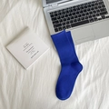 Vibrant blue cotton crew socks with ribbed texture on a minimalist white bedding setup - Sapphire Blue