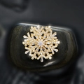 Rotating snowflake zircon brooch pin in gold finish on natural dark stone backdrop - Gold Snowflake Brooch