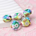 Macro shot of 5 colorful handmade animal glass beads with large holes for DIY jewelry - Caterpillar and White House