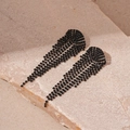 Detailansicht der schwarzen Strass-Quasten-Ohrringe auf einer hellen Natursteinplatte - V-Form Quaste Stil / Schwarz