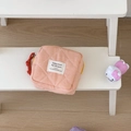 Close-up of quilted gingham storage bag with brand label and red zipper pull - Orange