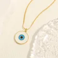 Detailaufnahme der goldenen Schlangenkette mit blauem Emaille-Anhänger auf Stoff - Stil B-Blaue Runde Scheibe