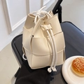 Sac seau tissé à la main blanc crème avec cordon de serrage sur une chaise noire - Blanc