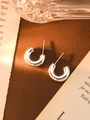 Detalle de pendientes plateados en forma de C sobre escritorio vintage con luz cálida natural - Plata Pequeño Forma C