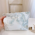 Gros plan sur la trousse à maquillage en jacquard avec broderie dorée et étiquette - Fleur Bleue Fil d'Or