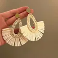 Detail of fan-shaped beige raffia woven earrings with golden metal studs in hand - 4# Steel Earring Post - Gold - White
