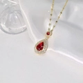 Elegante Goldhalskette mit rotem Tropfenanhänger und Mikro-Kristallbesatz auf weißer Seide - Rot