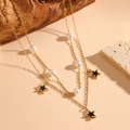 Detail view of double-layer gold necklace with pearls and black star pendants on wood - Gold Star Black Shell Necklace (C221)