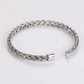 Macro-opname van de zilveren handgevlochten open armband met gedetailleerde weefstructuur - Staalkleur