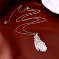 Macro shot of silver feather pendant with zircon pavé setting on luxury silk background - Feather Pendant Necklace / Silver