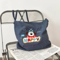 Detail of cute puppy embroidery on a blue striped canvas tote bag over newspapers - Pilot Dog