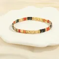 Detailed view of colorful Tila bead bracelet displayed on a white shell-shaped porcelain dish - Warm Orange & Beige Set