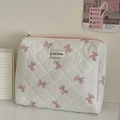 Nahaufnahme der gesteppten weißen Kosmetiktasche mit rosa Schleifenmuster und Label - Clutch Bag / Rosa Schleife