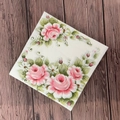 Square floral paper napkin with elegant pink rose pattern on dark wood background - Lotus