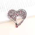 Spilla a cuore argento con cristalli rosa e trasparenti su sfondo di libro vintage - Viola