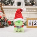 Gnome de Noël avec chapeau rouge et barbe verte tenant un panneau Merry Christmas - Style Masculin Haut Chapeau Rouge Tenant un Panneau Merry Christmas