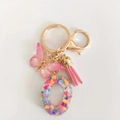 Pink resin letter O keychain with glitter hearts, butterfly charm and tassel details - Letter O