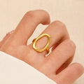 Detail eines minimalistischen goldenen ovalen Rings auf der Hand mit Stoffhintergrund - MY018 / Gold