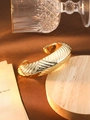 Golden plated open cuff bracelet with textured spiral design on a wooden pedestal - L160-1 Gold 3D Irregular