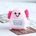 Close-up of pink handmade crochet axolotl doll holding a positive motivational card - Axolotl