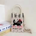 Detail of knitted beige cat bag showing black cat pattern and texture of woven fabric - 24 Phone Bag-Naughty Apple Cat