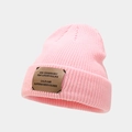 Close-up of pink ribbed knit beanie featuring a brown leather patch with logo detail - Pink