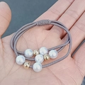 Taupe high-elasticity hair tie featuring white faux pearls and gold beads on a palm - Khaki