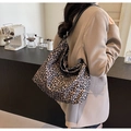 Borsa tote leopardata con ampia tracolla nera mostrata in un ambiente di caffè - Nero