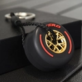 Black racing tire keychain with a golden multi-spoke rim and red Zero branding detail - Red