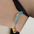 Elegante bracciale dorato con perline turchesi blu e chiusura intrecciata sul polso - Blu