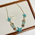 Detail of starfish enamel charms with faux pearls and red gems on a gold chain - Blue Starfish Necklace I-13