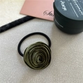 Detailed view of a green velvet rose hair tie on a minimalist textured gray background - Army Green