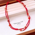 Dettaglio di collana di perline rosse con tocchi dorati in una scatola di velluto beige - Rosso