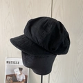 Detail view of a black cotton octagonal cap on a display head with artistic background - Black
