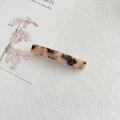 Close-up of a tortoiseshell acetate hair clip with spring fastener on textured background - Light Tortoiseshell