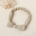 Macro detail of beige cotton baby headband with bow and elastic texture - Khaki