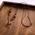 Macro detail of amber leopard print heart pendant with gold rim on woven black cord - Black Cord Amber Flower Necklace