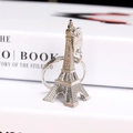 Silberner Eiffelturm Schlüsselanhänger mit Paris-Gravur auf weißem Buchhintergrund - Silber