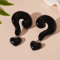 Detailed view of black resin heart and question mark earrings on beige backdrop - Black