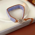 Details des geflochtenen Lederarmbands mit hellblauen Steinen und Gänseblümchen-Verschluss - Blau