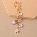 Dettaglio portachiavi dorato con ciondolo a lettera U e fiori in smalto bianco - Fiori Bianchi (U)