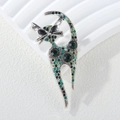 Gros plan d'une broche chat argentée ornée de strass brillants verts et noirs - Vert
