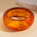 Macro shot of amber resin geometric bangle with tortoise shell texture on beige background - Amber