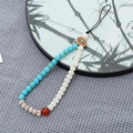 Detailed macro of white bodhi beads and blue turquoise stones on a phone lanyard - Turquoise + Bodhi Bead Style