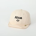 Dettaglio del ricamo Nice e dell'etichetta in tessuto su questo cappellino in cotone crema - 50cm 1-3 Anni / Bianco Sporco