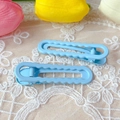 Close-up of a pair of light blue wavy plastic hair clips on white lace background - Blue