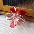 Detailed macro view of a red gradient plumeria flower hair claw clip with metal spring - Red Transparent