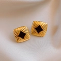 Vue détaillée de boucles d'oreilles vintage dorées avec centre en émail noir sur tissu - Clous d'oreilles carrés texturés en émail avec tige en acier plaqué or 18 carats