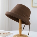 Brown breathable bucket hat with metal tag and tie on minimalist wooden display - M (56-58cm) / Brown